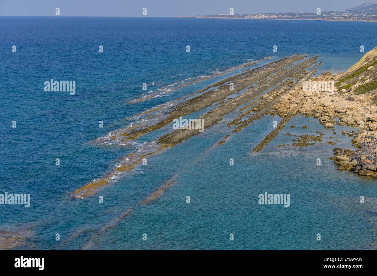 A mezzogiorno, le onde tranquille si infrangono dolcemente contro le impressionanti formazioni rocciose, creando una vista ipnotica della bellezza della natura lungo la costa, invitante Foto Stock