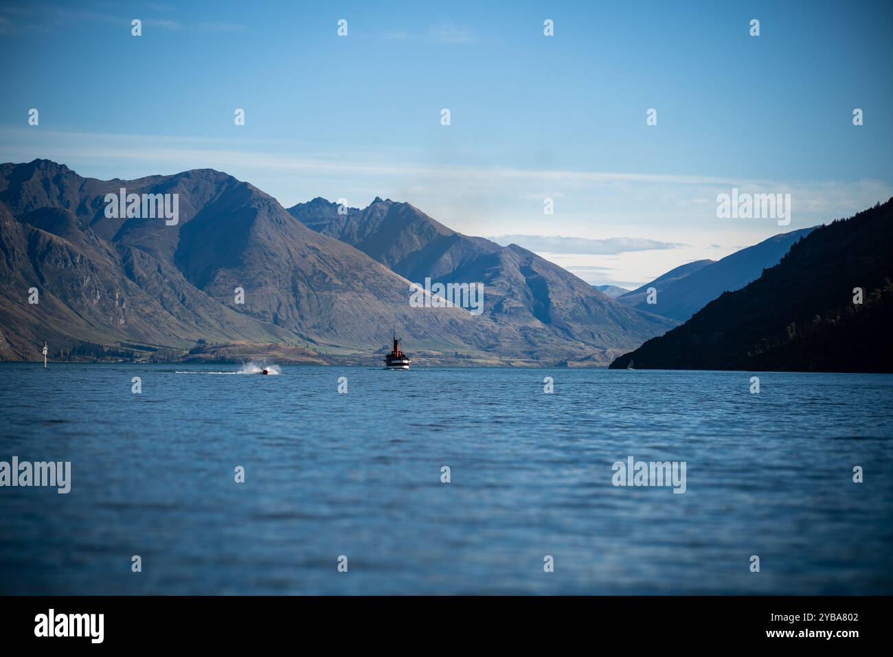 Vista panoramica del lago Wakatipu e delle montagne circostanti con il cielo sullo sfondo; sono in vista anche navi da diporto e motoscafi. Foto Stock