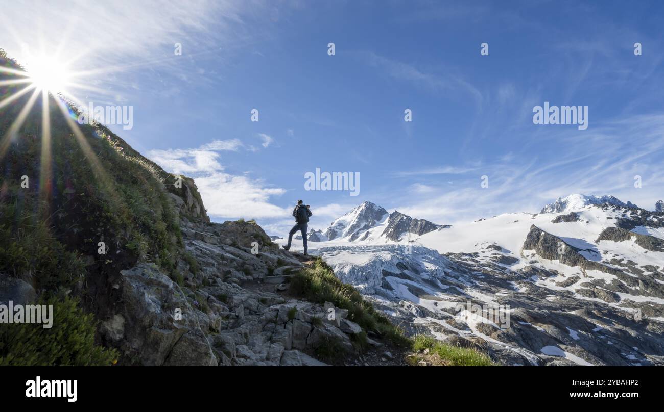 Alpinista di fronte al paesaggio di alta montagna alpina con stella del sole, cima dell'Aiguille de Chardonnet e del Glacier du Tour, ghiacciaio e cime montuose Foto Stock