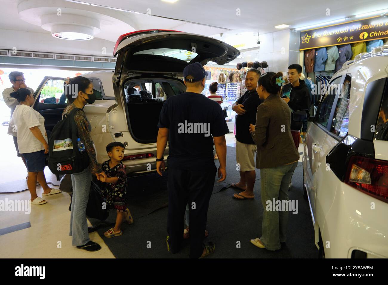 Un venditore di auto che mostra un SUV PHEV Dfsk Fengon E5 di fabbricazione cinese ai clienti all'ingresso del centro commerciale Talat Sao. Vientiane, Laos Foto Stock
