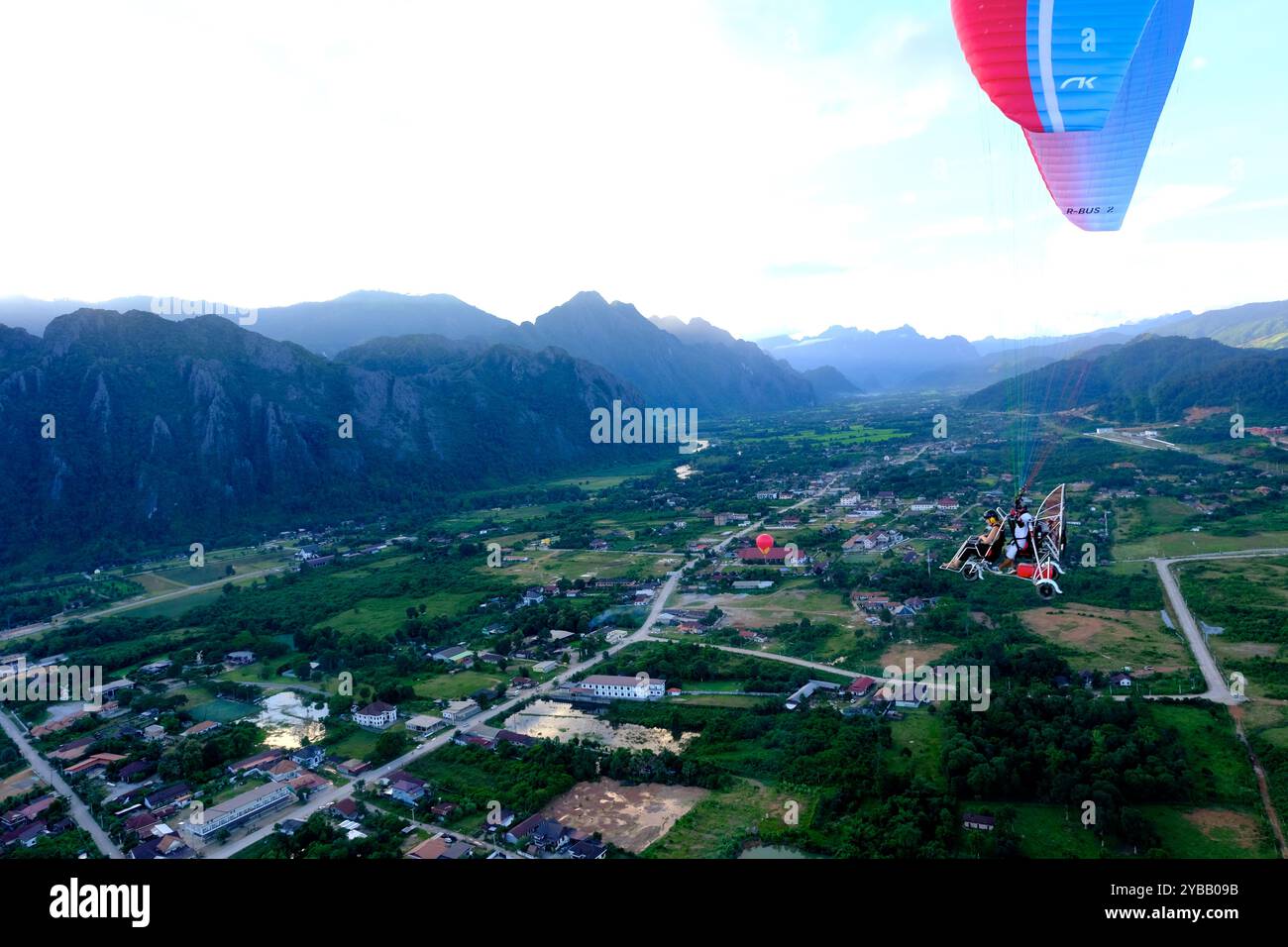 I paramotori trasportano turisti che volano sopra la città di Vang Vieng, Laos Foto Stock