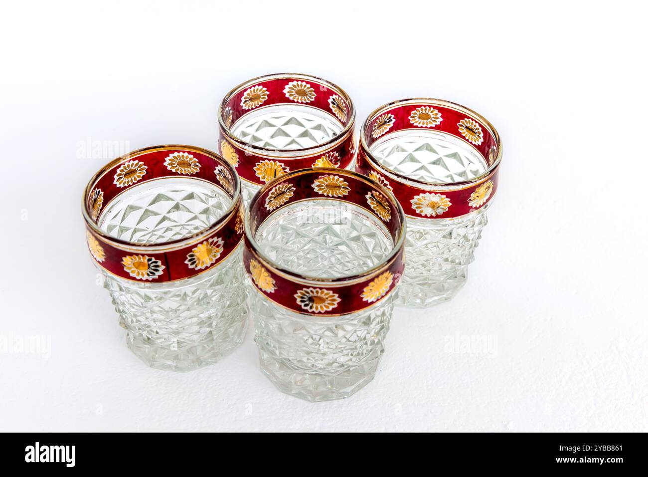 Un gruppo di quattro bicchieri di cristallo vintage con bordi decorati, isolati su uno sfondo bianco. Foto Stock