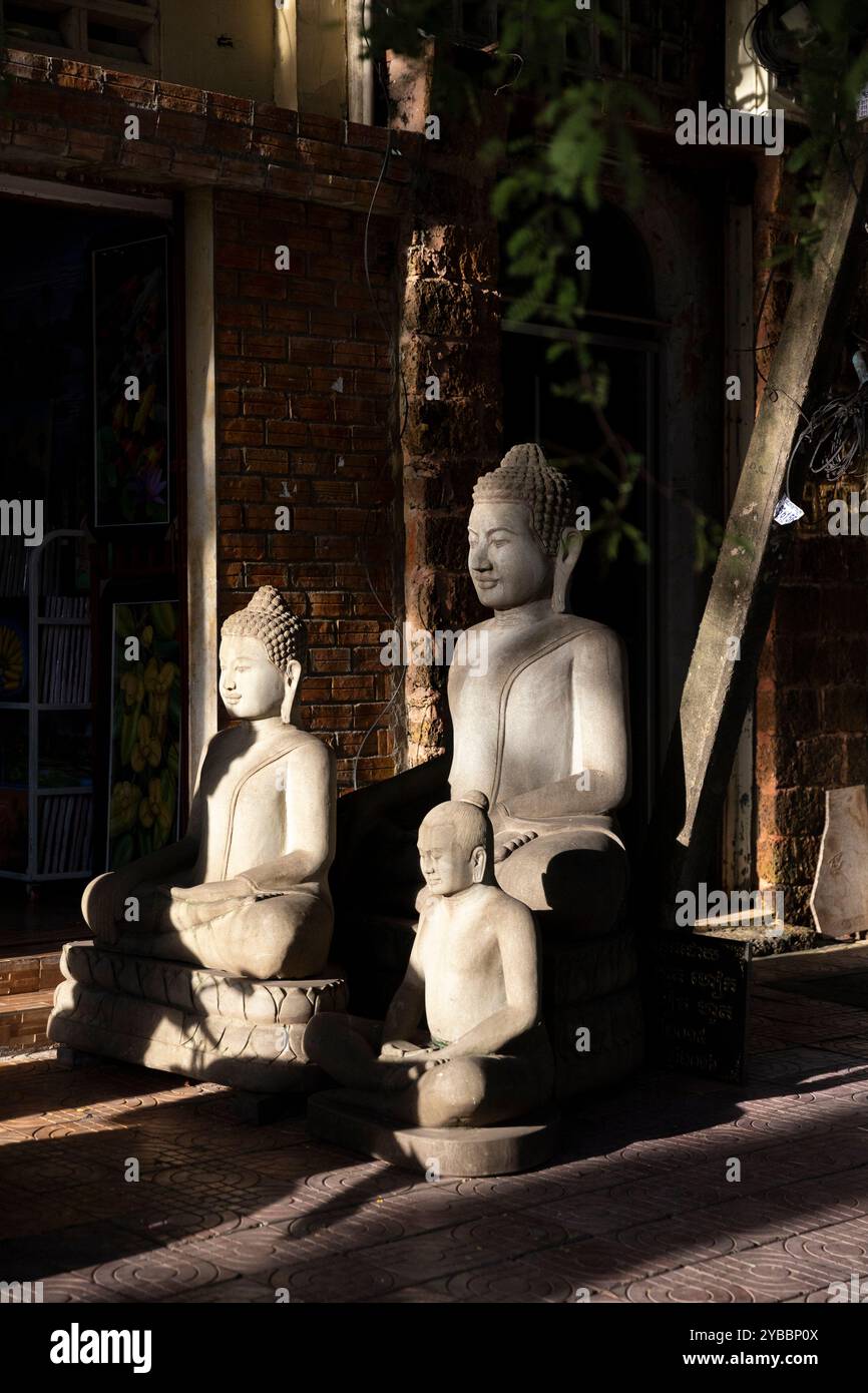 Le serene statue di Buddha si stagliano su una strada tranquilla nel centro di Phnom Penh, in Cambogia, bagnata dal caldo bagliore del sole che tramonta. Foto Stock