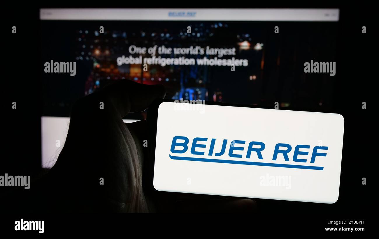 Persona che detiene uno smartphone con il logo della società svedese di HVAC Beijer Ref AB sullo schermo di fronte al sito Web. Mettere a fuoco il display del telefono. Foto Stock