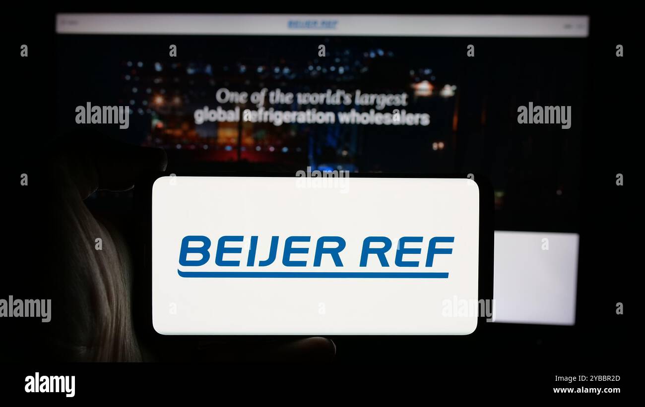 Persona che detiene un cellulare con il logo della società all'ingrosso HVAC svedese Beijer Ref AB sullo schermo davanti alla pagina Web. Mettere a fuoco il display del telefono. Foto Stock