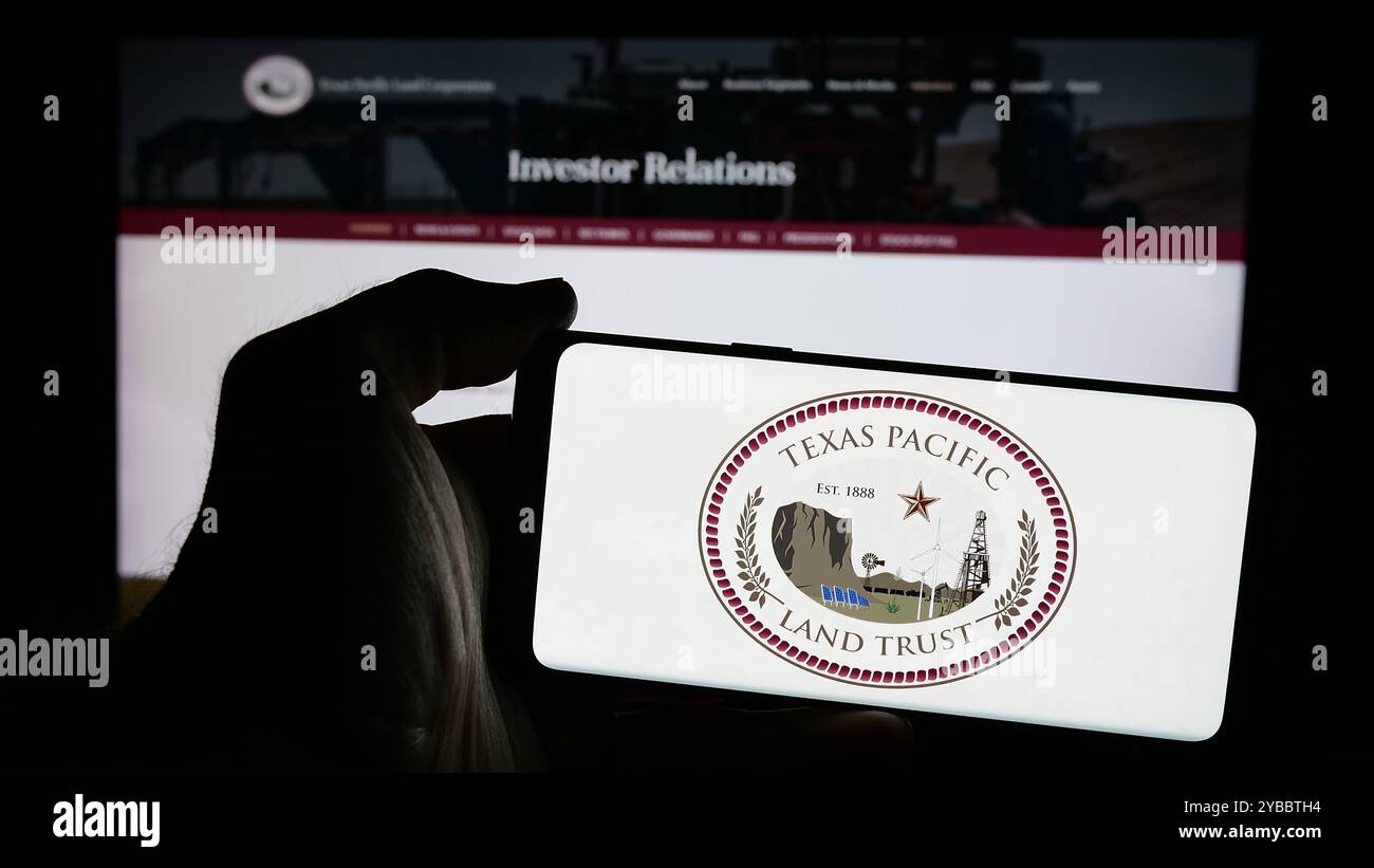 Persona che detiene un cellulare con il logo della società statunitense Texas Pacific Land Corporation sullo schermo di fronte alla pagina Web aziendale. Mettere a fuoco il display del telefono. Foto Stock