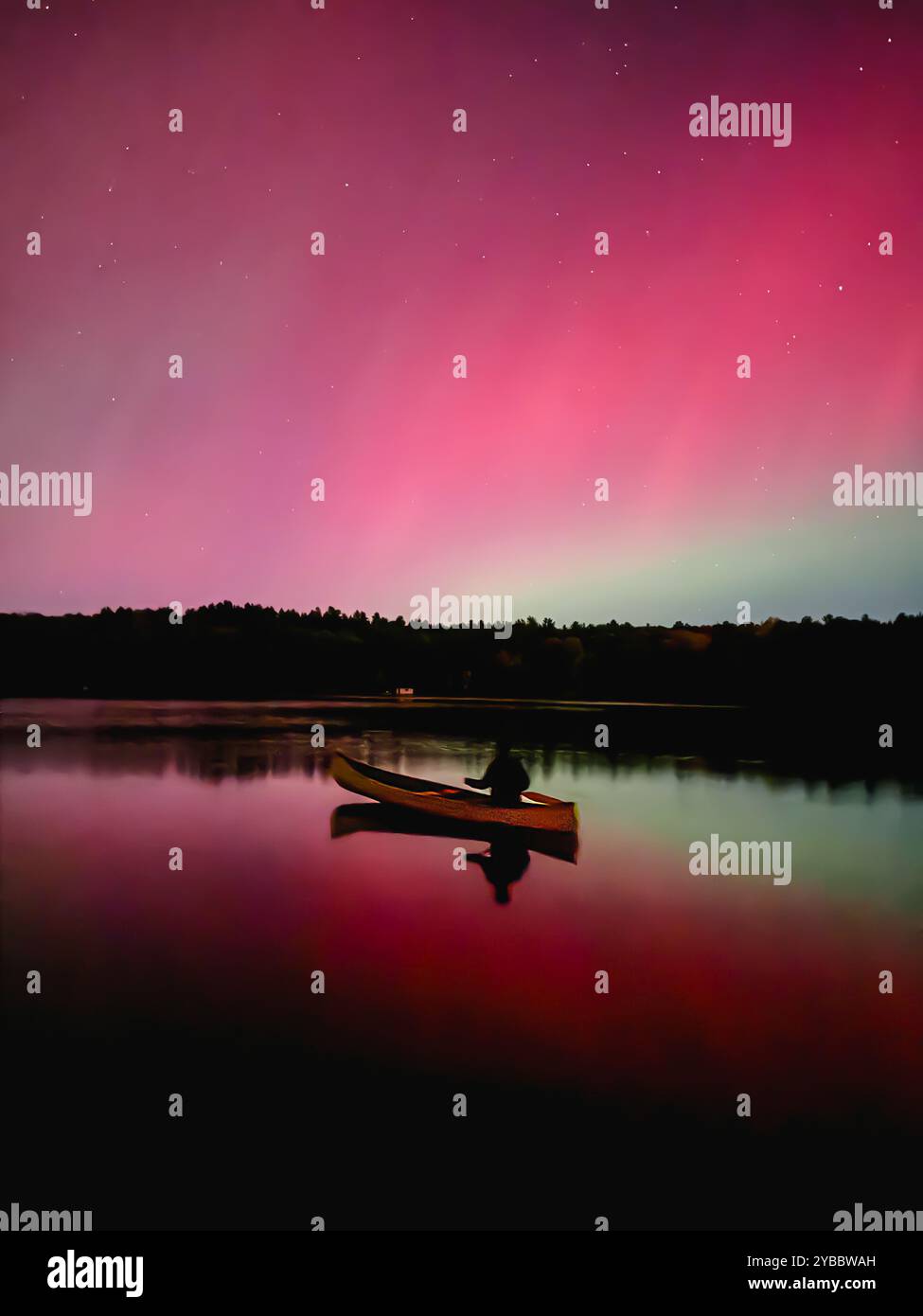 Persona in canoa sul lago che guarda l'aurora boreale rossa/rosa. Foto Stock