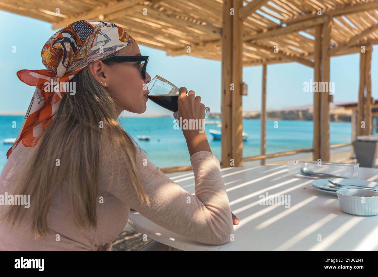 Una donna è seduta a un tavolo con un bicchiere di birra davanti a lei Foto Stock
