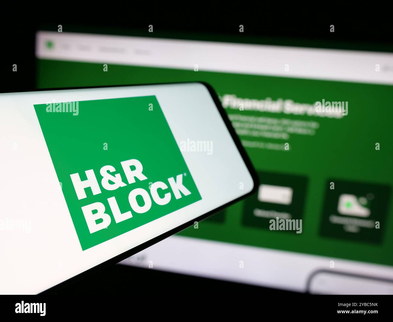 Cellulare con logo della società americana di preparazione fiscale HR Block Inc. Sullo schermo davanti al sito Web. Mettere a fuoco la parte centrale sinistra del display del telefono. Foto Stock