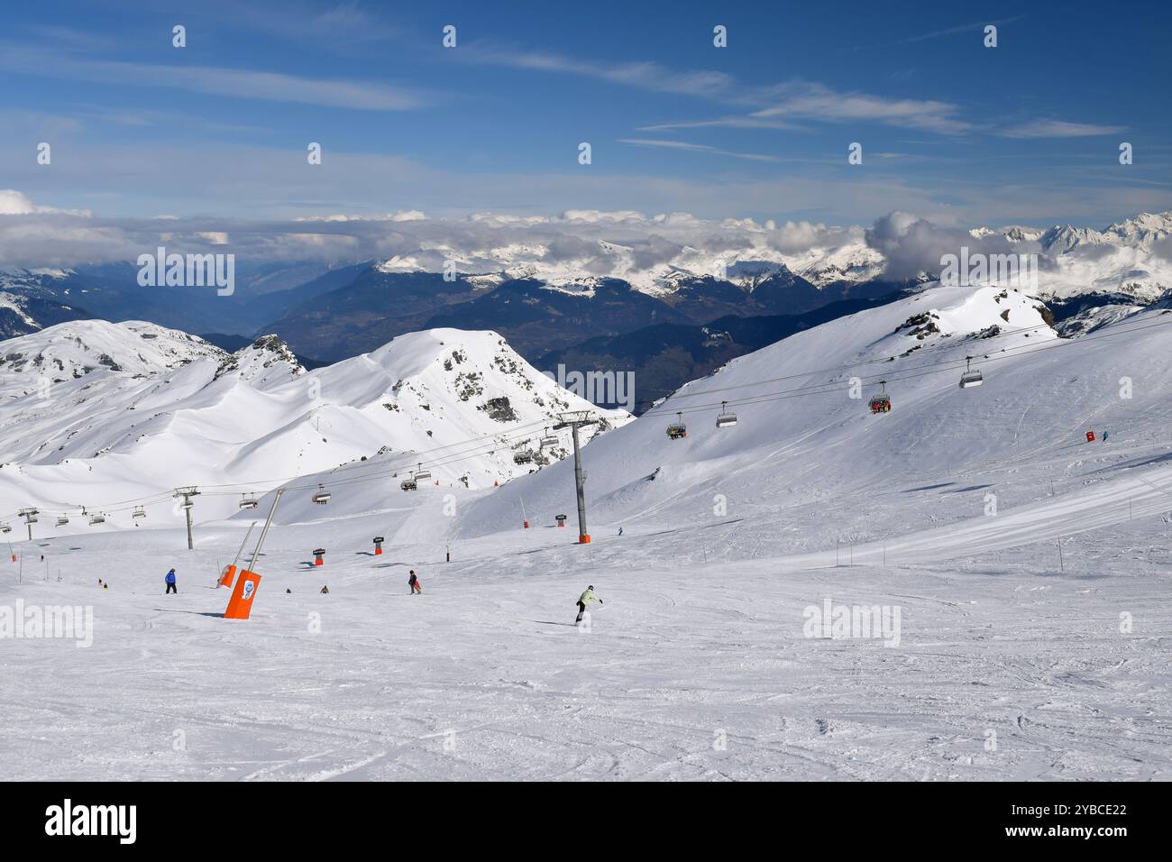 Sciatori e snowboarder che scendono sulle piste della stazione sciistica Les Menuires. Attività sportive invernali con vista sulle montagne innevate nelle tre valli. Foto Stock