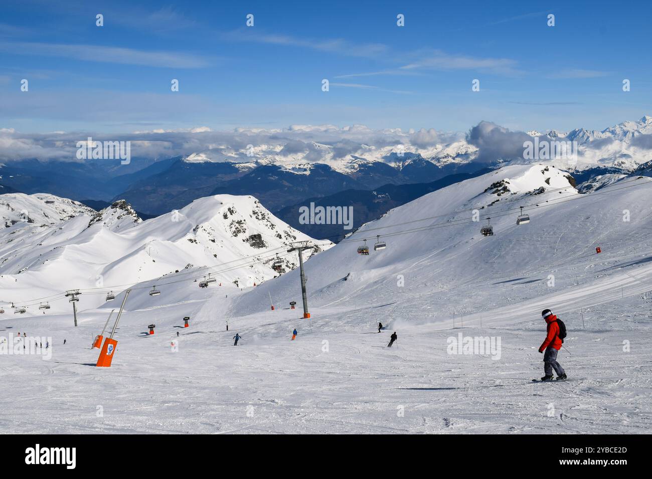 Sciatori e snowboarder che scendono sulle piste della stazione sciistica Les Menuires. Attività sportive invernali con vista sulle montagne innevate nelle tre valli. Foto Stock