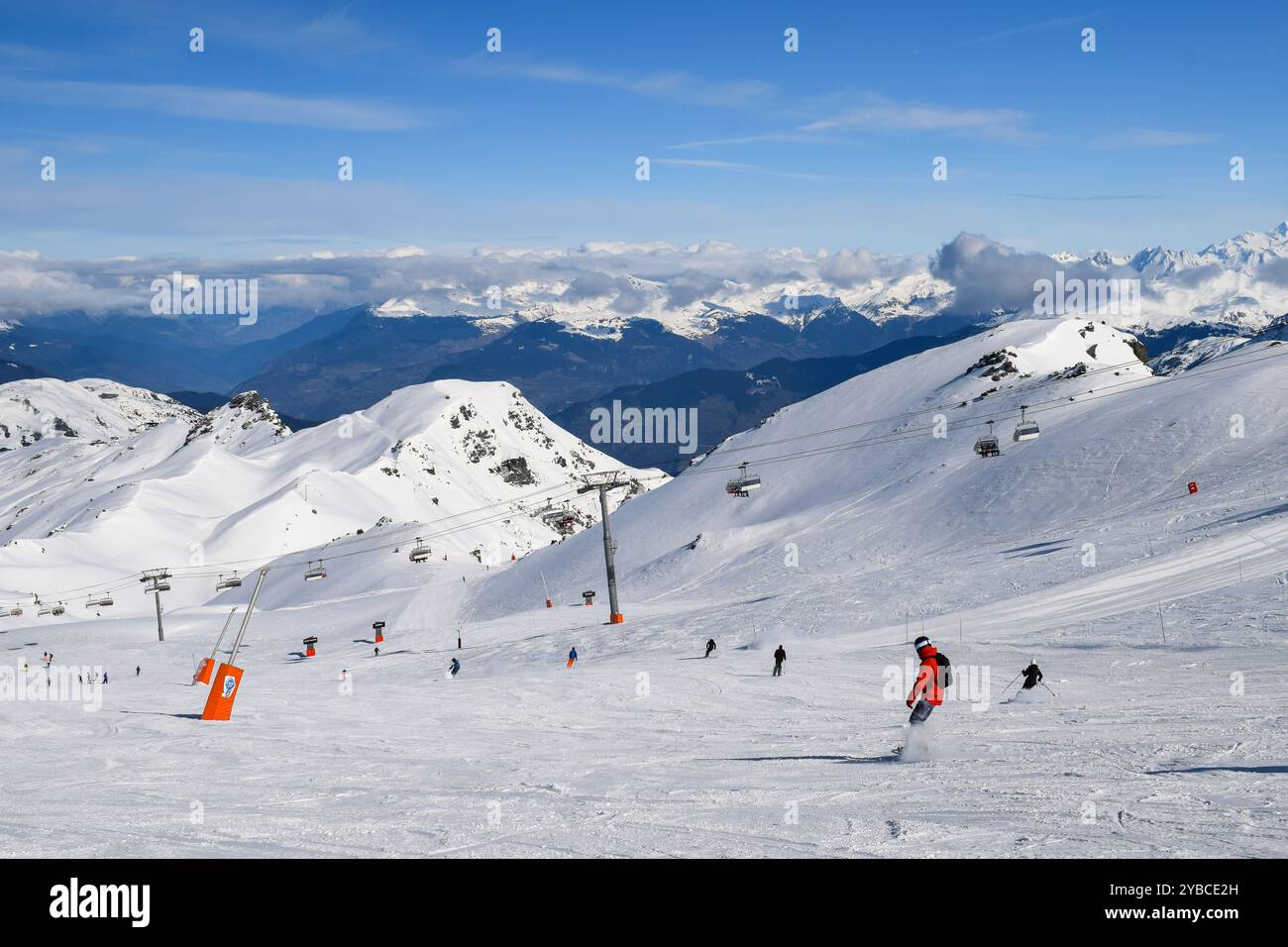 Sciatori e snowboarder che scendono sulle piste della stazione sciistica Les Menuires. Attività sportive invernali con vista sulle montagne innevate nelle tre valli. Foto Stock