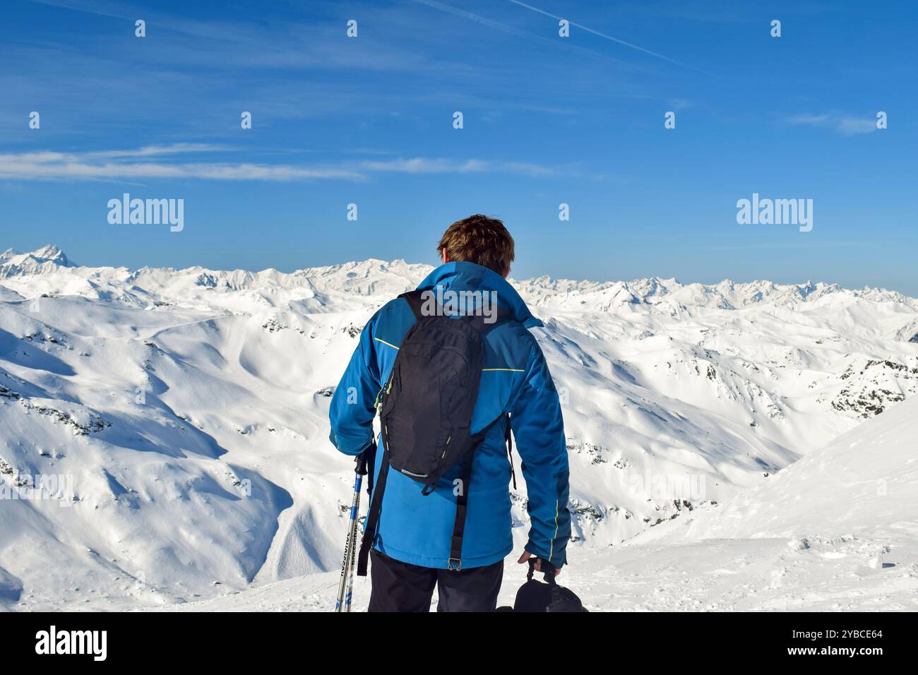 Sciatore maschile che guarda le vette mozzafiato innevate delle tre Valli. Uomo avventuroso all'aperto ad alta quota sulle cime innevate delle montagne Foto Stock