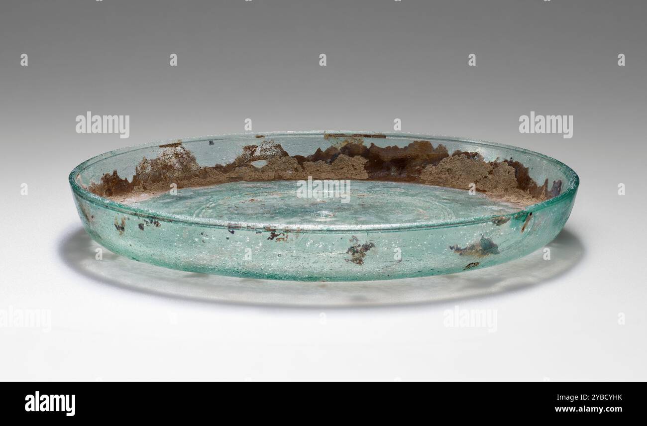 Piatto, 2°-3° secolo d.C. informazioni aggiuntive: Piatto fuso di vetro blu-verde traslucido. La piastra è circolare con un bordo a parete alta. Le incisioni tagliate formano un cerchio centrale con altri due anelli concentrici tagliati a circa metà tra il centro e la parete. Tra il muro e il fondo si verificano degli agenti atmosferici e degli incroci. C'è una leggera iridescenza. Foto Stock