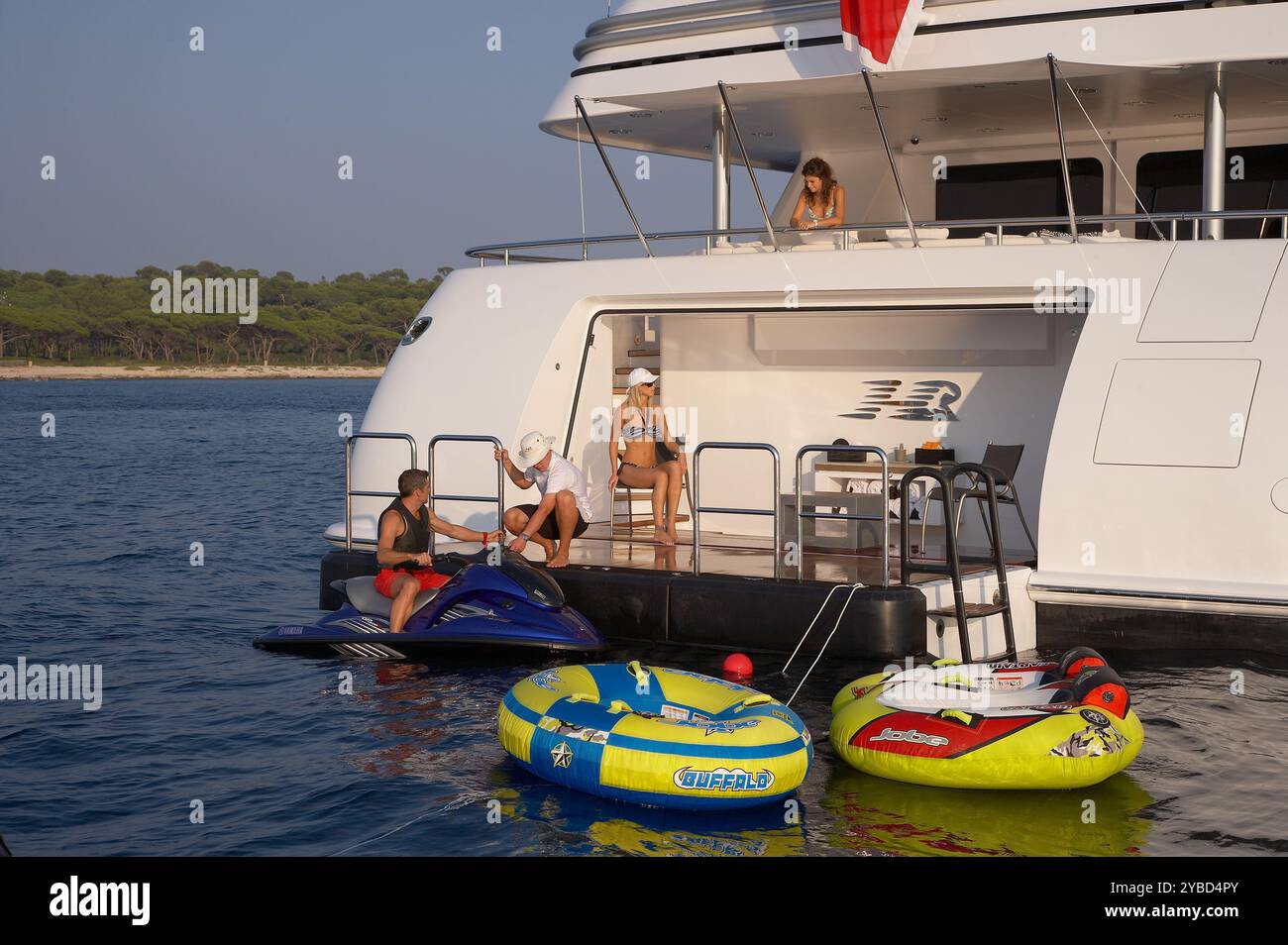Noleggiate gli ospiti in vacanza godendovi la piattaforma da nuoto su un superyacht con i giocattoli d'acqua in primo piano. Foto Stock Noleggiate gli ospiti in vacanza godendovi la piattaforma da nuoto su un superyacht con i giocattoli d'acqua in primo piano. Foto Stock