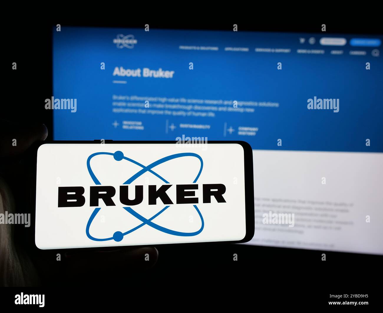 Persona che detiene lo smartphone con il logo della società statunitense Bruker Corporation sullo schermo di fronte al sito Web. Mettere a fuoco il display del telefono. Foto Stock