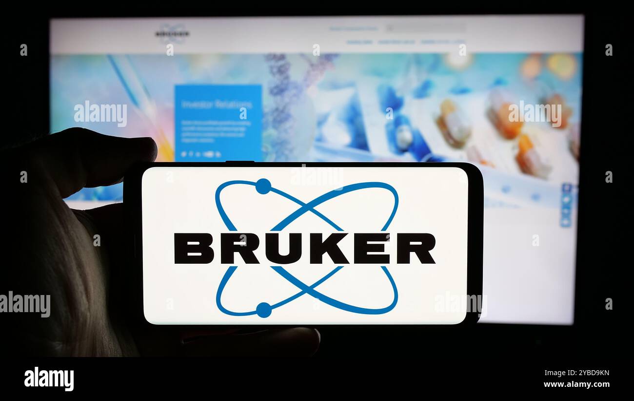 Persona che detiene un cellulare con il logo della società statunitense Bruker Corporation sullo schermo di fronte alla pagina Web aziendale. Mettere a fuoco il display del telefono. Foto Stock