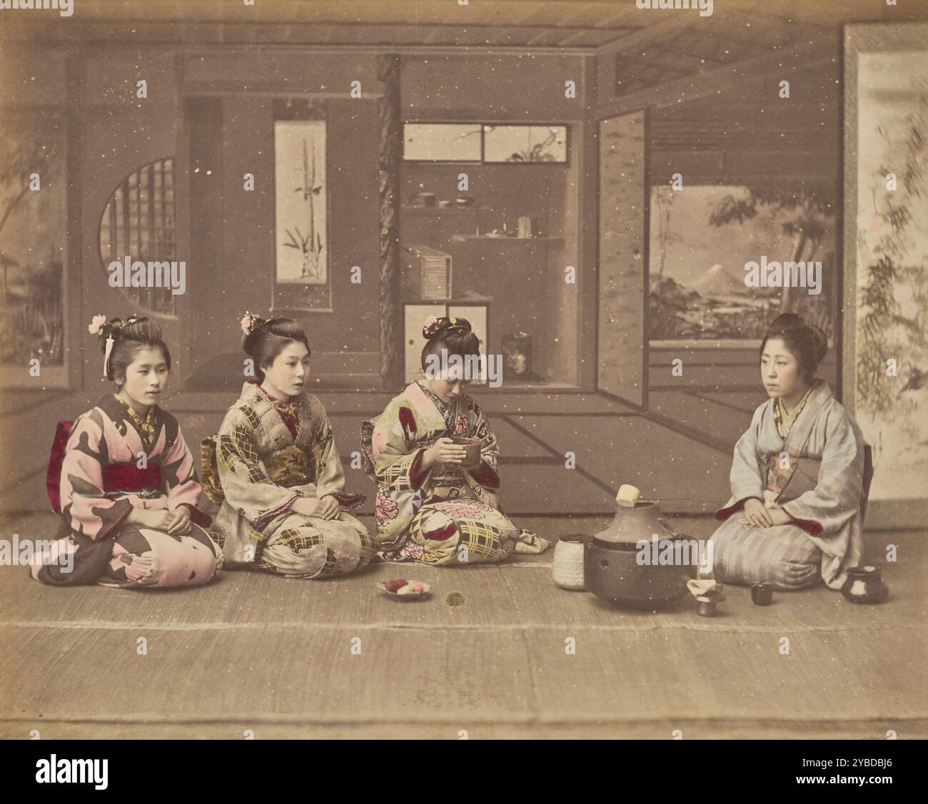 Cerimonie giapponesi del tè, circa 1875-1890 Quattro donne sono sedute intorno a un braciere di ferro tipicamente utilizzato in una cerimonia del tè giapponese. Una delle donne guarda in basso un "chawan" o una ciotola da tè che tiene in mano. Lo sfondo dipinto presenta un "tokonoma", o alcova, con un rotolo sospeso e altri oggetti. Foto Stock