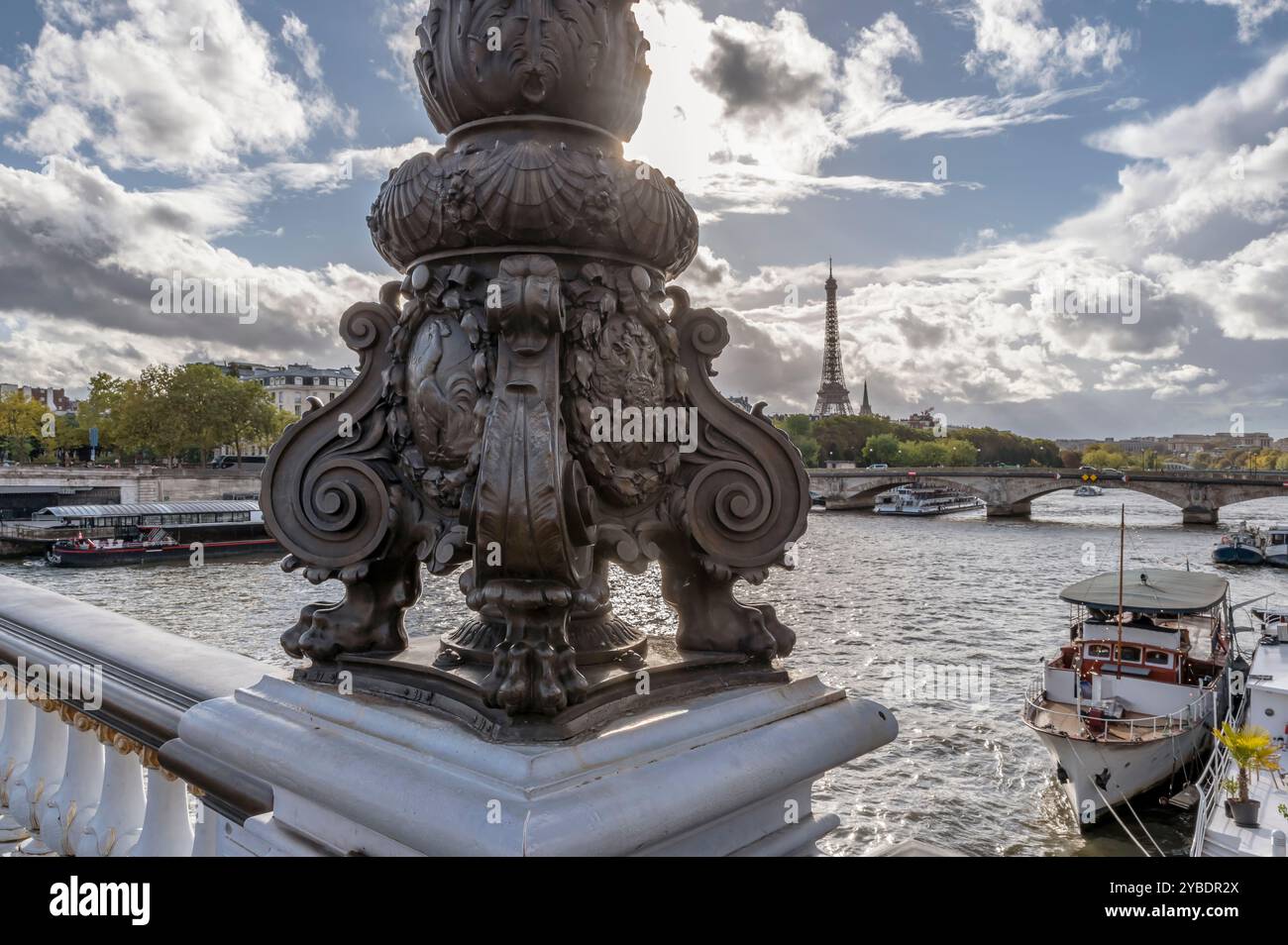 Il sole illumina i dettagli di un lampione sul ponte Alexandre III a Parigi, in Francia, con la Torre Eiffel sullo sfondo Foto Stock