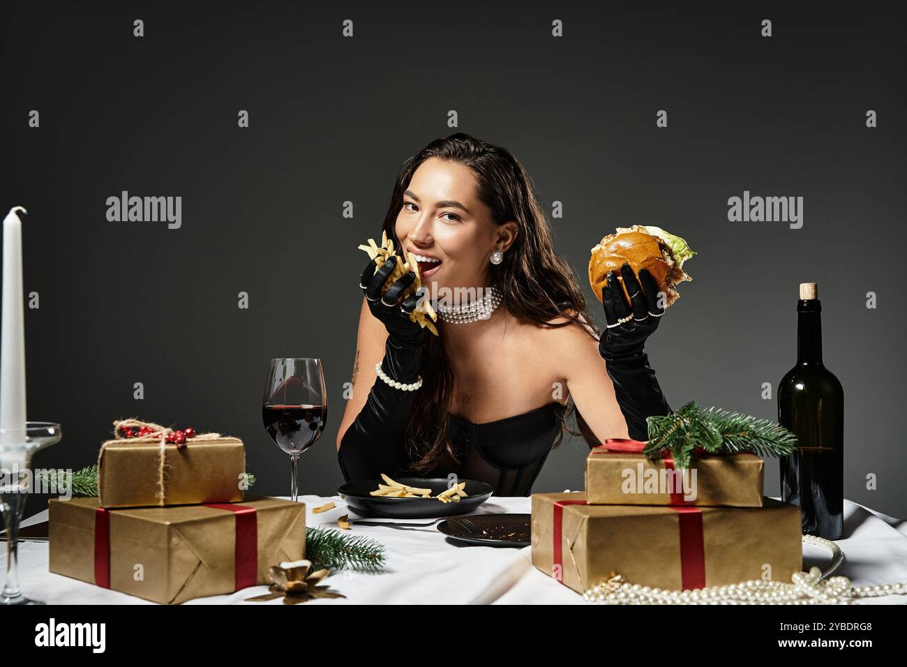 Una giovane donna delizia la cucina gourmet mentre siede ad un tavolo splendidamente decorato. Foto Stock