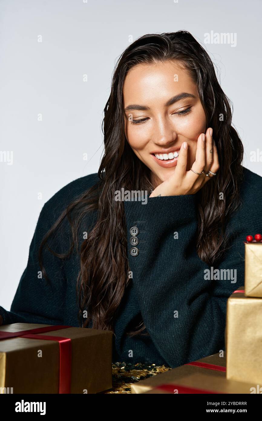 Una giovane donna con un sorriso brillante svela i regali in un arredamento splendido. Foto Stock