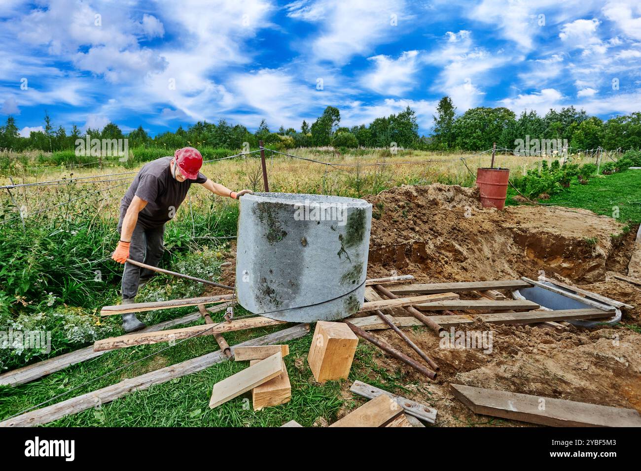 Il lavoratore sposta l'anello di calcestruzzo utilizzando un piatto a rulli realizzato con tubi e pannelli in acciaio. Foto Stock