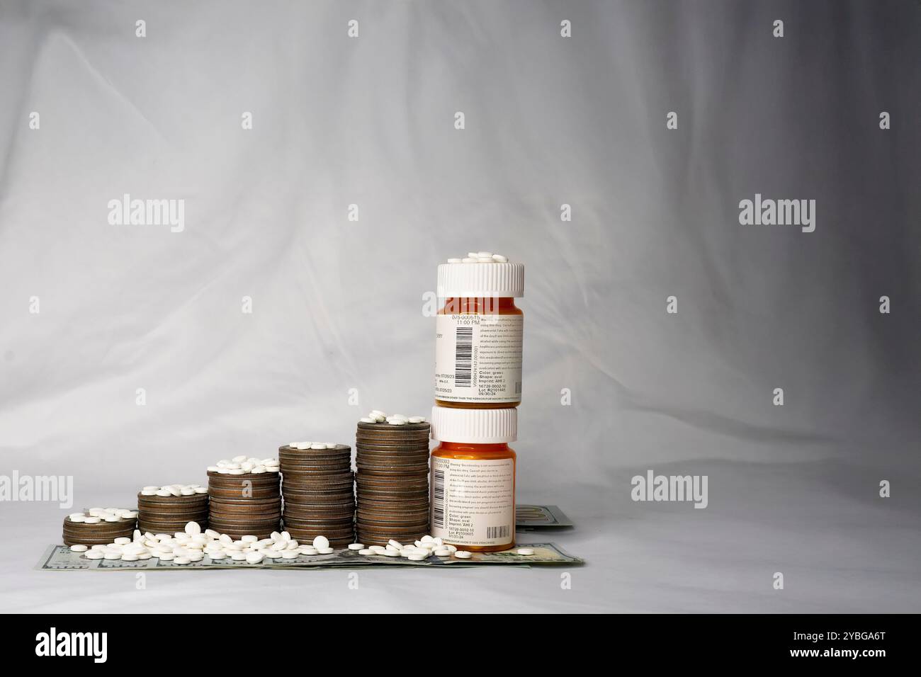 Compresse da prescrizione cosparse sopra una scala di soldi. Dollari d'argento e banconote da cento dollari con bottiglie di droga impilate formano la base. Foto Stock