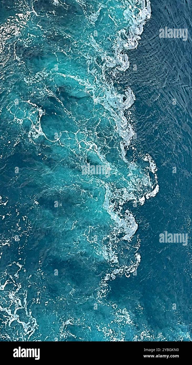 Splendida vista dall'alto di un oceano blu con onde dolci, sfumature turchesi e luce del sole che si riflette sull'acqua, creando una scena pacifica ed estetica. Foto Stock