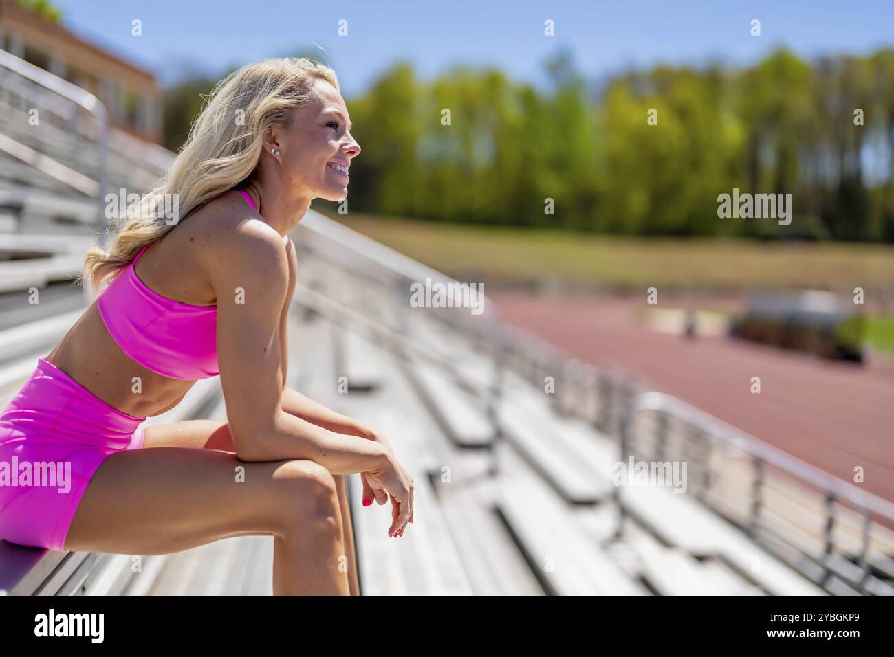Un radioso atleta bionda brilla in pista in una giornata straordinaria, incarnando forza e grazia a ogni passo Foto Stock