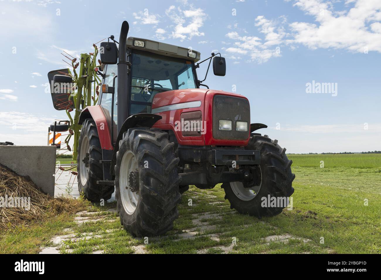 Trattore rosso con trefolo nelle vicinanze di un campo Foto Stock