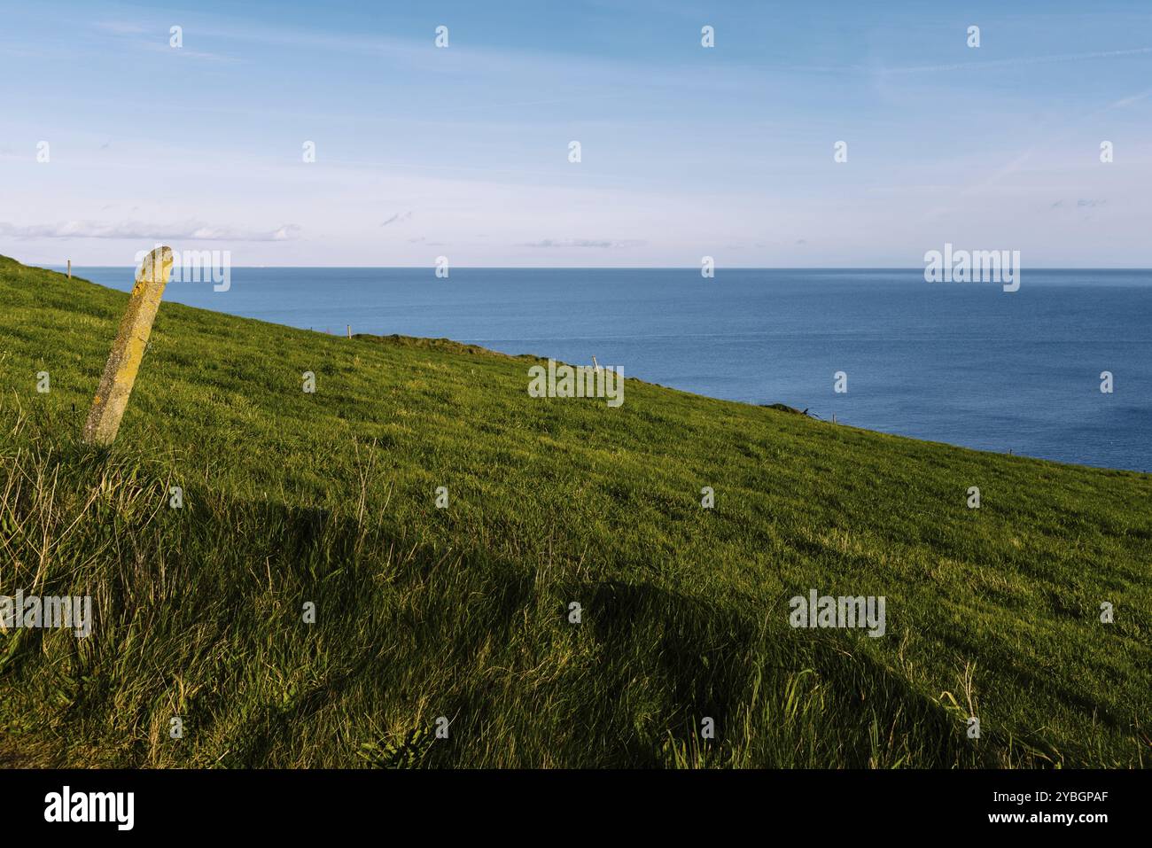 Vista panoramica della collina verde e dell'oceano Atlantico sulla costa irlandese al tramonto Foto Stock