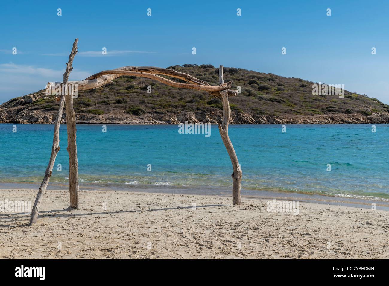 Una cornice di tronchi di legno sulla spiaggia di Tuerredda, Sardegna, Italia e sull'isola di Tuaredda sullo sfondo Foto Stock