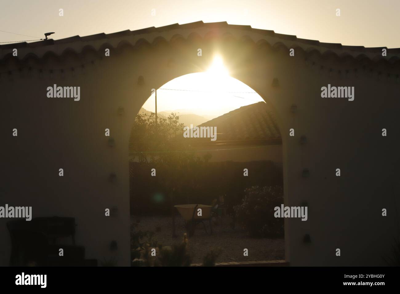 il sole splende attraverso il cancello di un muro Foto Stock