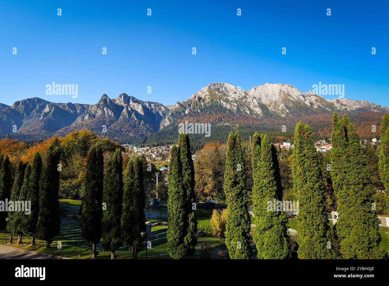 I monti Bucegi e il picco Caraiman sullo sfondo e la città di Busteni durante una giornata di sole autunno. Foto Stock