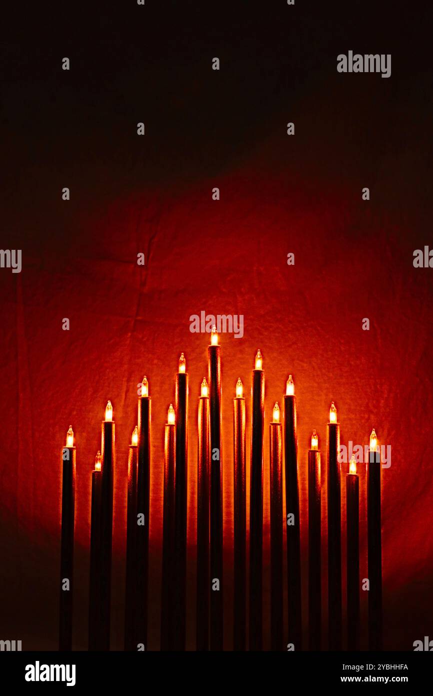 Candele elettriche o candelabri bruciati su sfondo rosso sangue. Copia spazio in cima all'immagine. Adatto per immagini di copertina di libri, ecc. Foto Stock