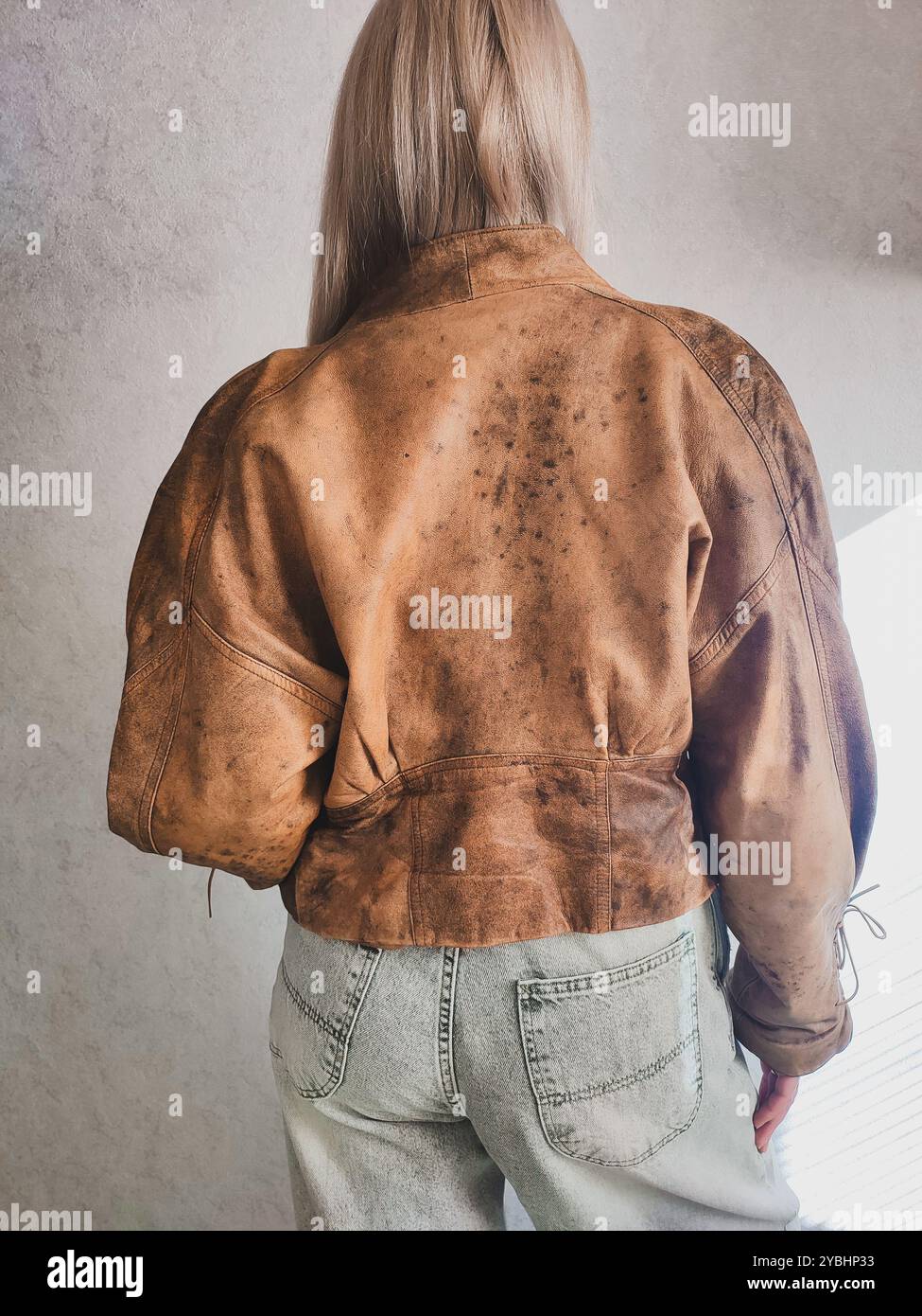 Giacca in pelle marrone vintage sul retro di una donna dai capelli biondi, giacca grunge corta, bolero da donna in similpelle, giacca in pelle con lacci anni '80 anni '90, abiti da donna vintage, outfit retrò - Immagine stock catturata con smartphone
