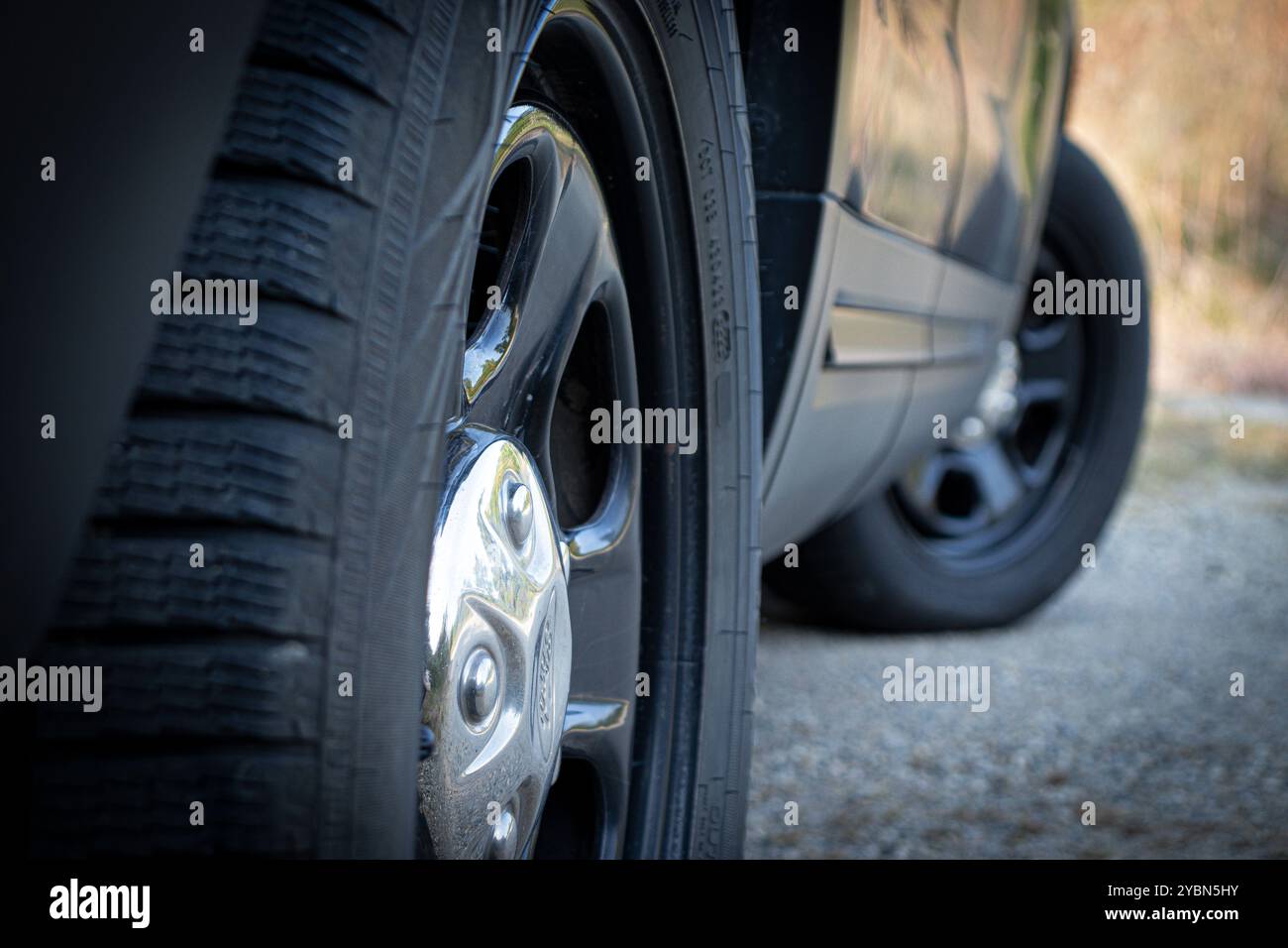 Primo piano delle ruote in acciaio e dei tappi cromati di un'auto poliziesca Foto Stock