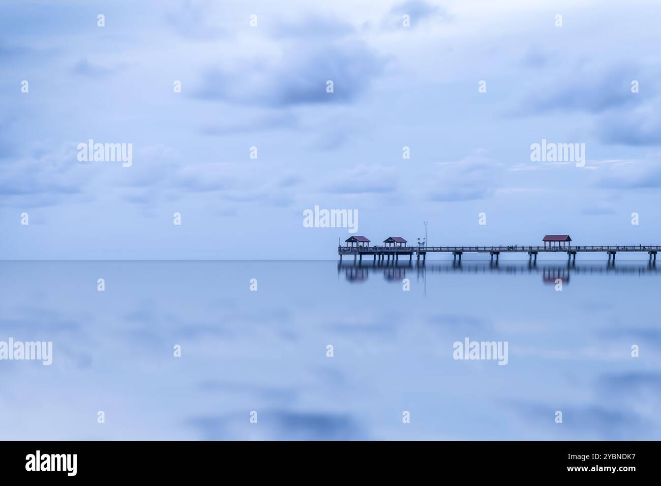 Una vista tranquilla del molo di Clearwater Beach, Florida, USA. Il lungo molo si estende su acque calme e riflettenti, con piccole capanne arroccate. Foto Stock