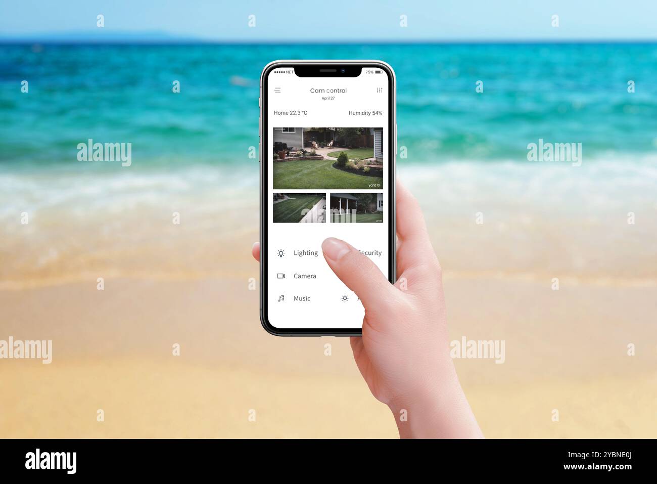 Monitoraggio delle telecamere di sicurezza domestiche dalla spiaggia tramite un'app per smartphone, per garantire tranquillità durante una vacanza al mare e tenere d'occhio la situazione Foto Stock
