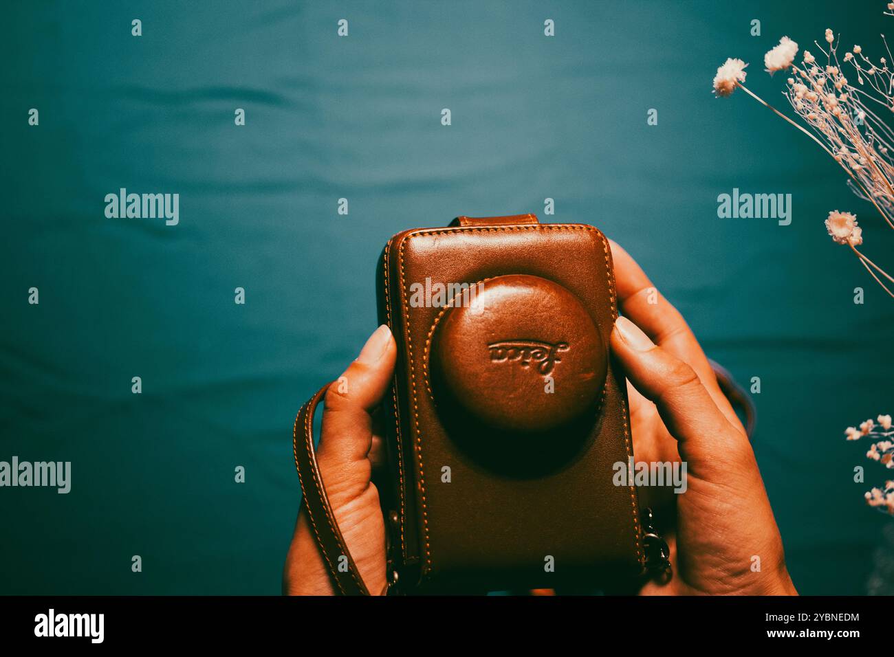 Madrid, Spagna. 1° maggio 2023 fotocamera Leica d'epoca in custodia in pelle marrone con mani femminili su sfondo blu. Hobby per la fotografia retrò. Fotografo. Foto Stock