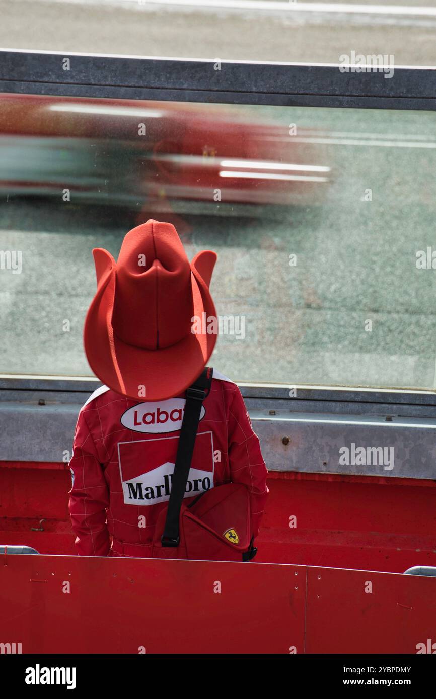 Spettatore con enorme cappello rosso Ferrari che guarda la Ferrari F1 Clienti al circuito Enzo e Dino Ferrari, Imola, Italia Foto Stock