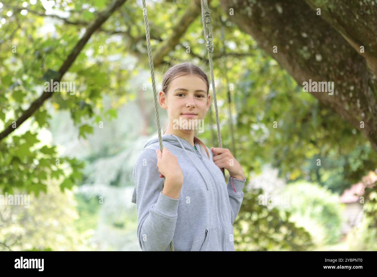 Ragazza in altalena in giardino d'estate sotto l'albero Foto Stock