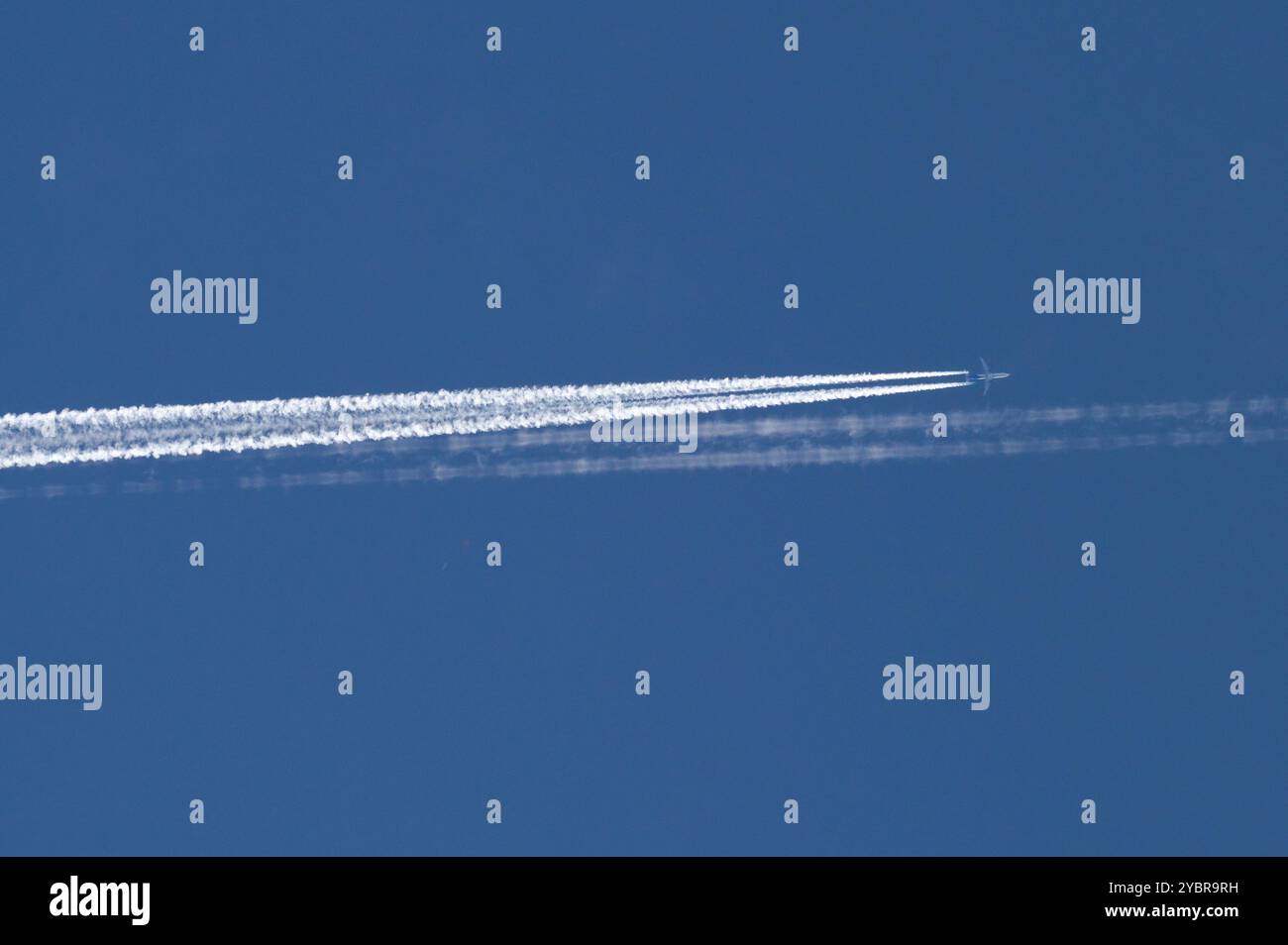 L'aereo da trasporto fa la linea di tracce molto forte delle scie chimiche sul cielo blu. Linea chemtrail doppia. Teoria della cospirazione. Foto Stock