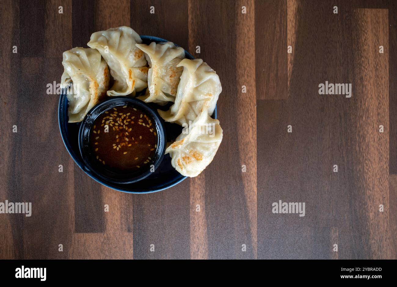 Gyoza giapponese tradizionale con carne e salsa di soia su un tavolo di legno. Foto Stock