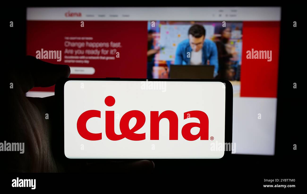 Persona che detiene un cellulare con il logo della società statunitense di sistemi di rete Ciena Corporation sullo schermo davanti alla pagina Web. Mettere a fuoco il display del telefono. Foto Stock