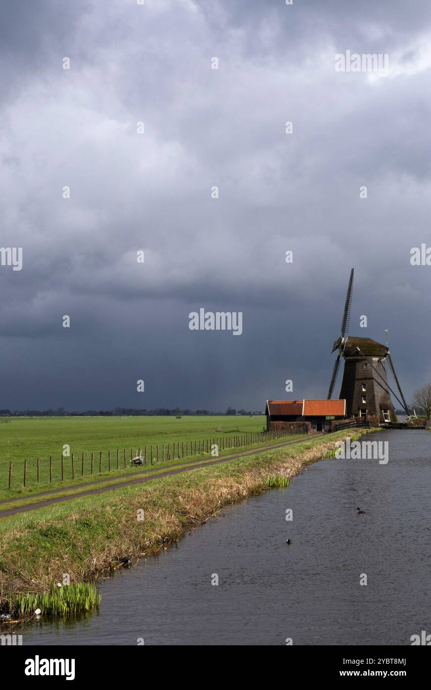 Mulino a vento Dikke Molen vicino ad Alphen aan den Rijn con alcune nuvole di pioggia in avvicinamento Foto Stock