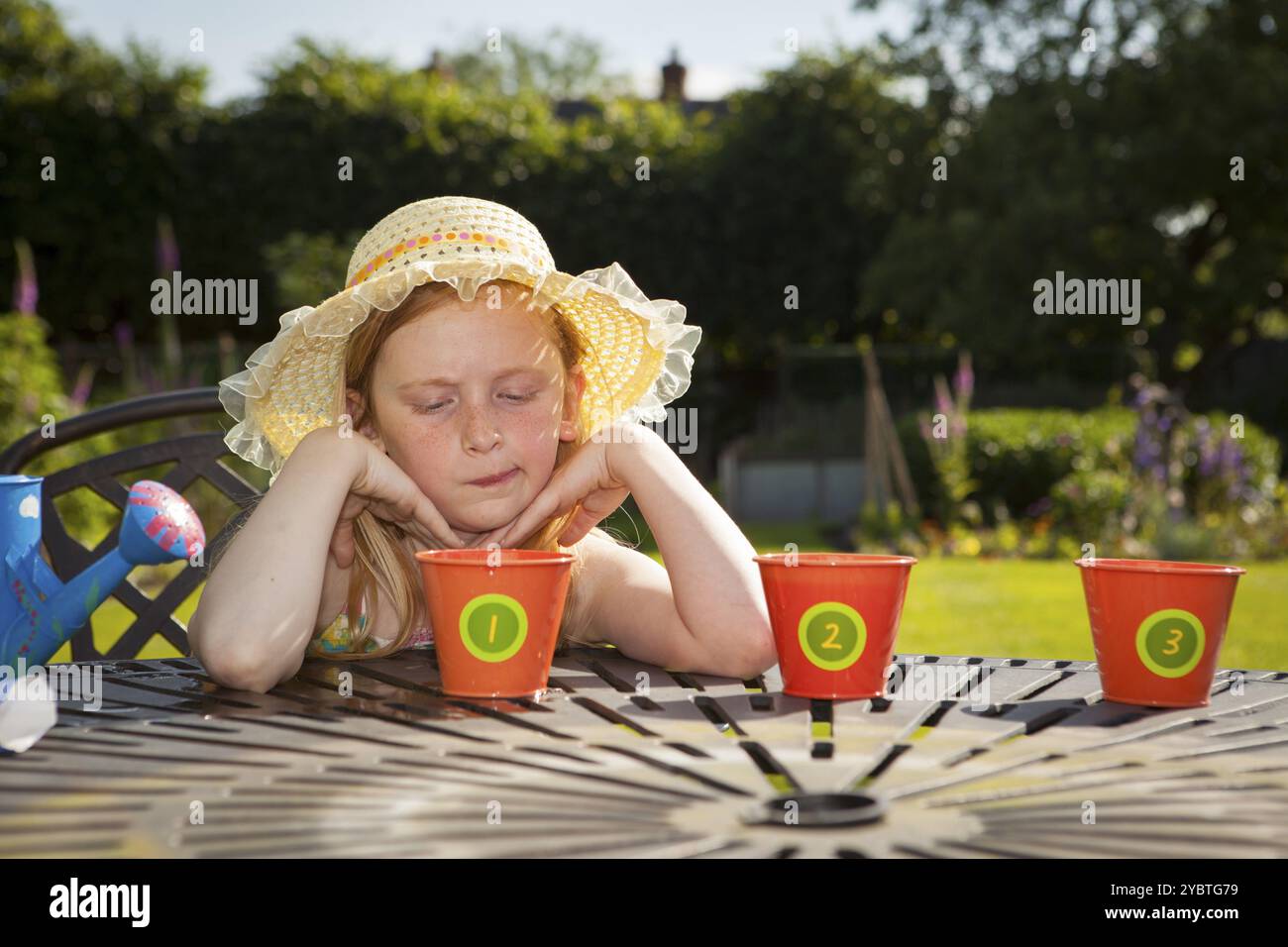 Pre teen ragazza caucasica annaffiare vasi di fiori in un giardino temi di attesa impazienza cura del giardiniere Foto Stock