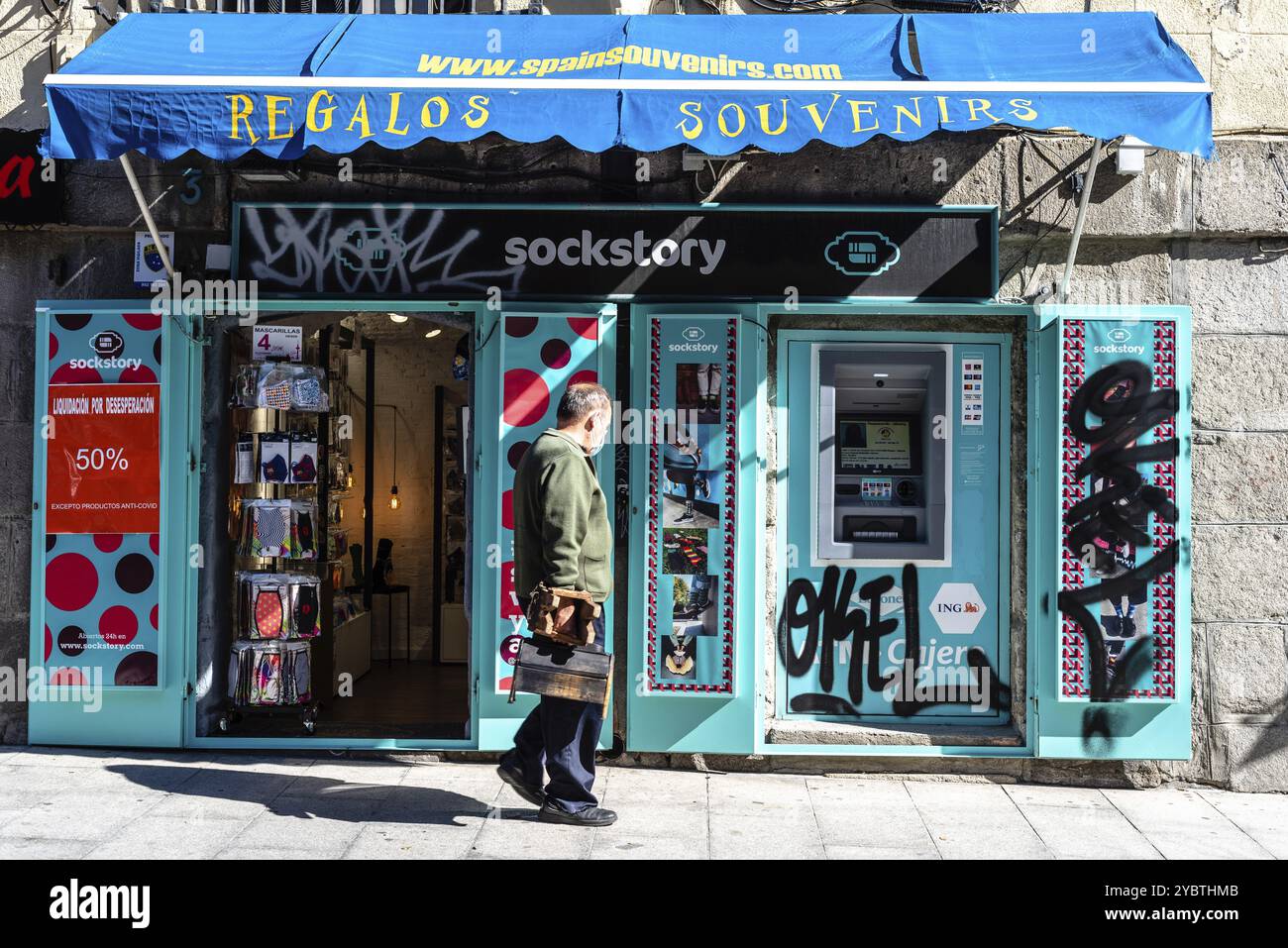 Madrid, Spagna, 11 ottobre 2020: Uomo in piedi di fronte a un negozio di souvenir e regali nel centro di Madrid. Bancomat vandalizzato sulla facciata dello sto Foto Stock