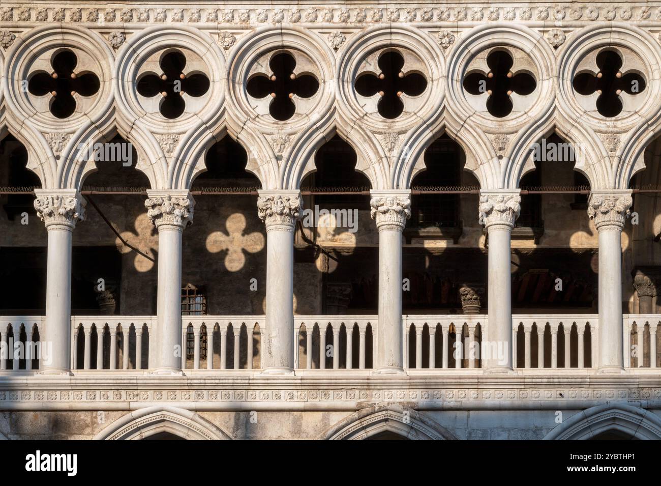 Facciata geometrica di Palazzo Ducale con colonne a Venezia in Italia in Europa durante il tramonto con la luce del sole che cade sull'esterno Foto Stock