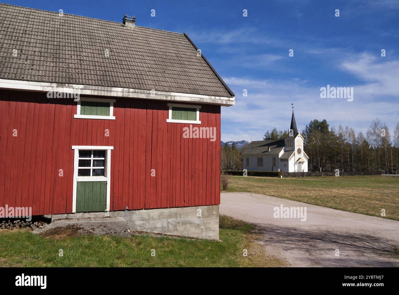 La chiesa del villaggio norvegese Vradal visto dietro un dipinto falured capannone Foto Stock